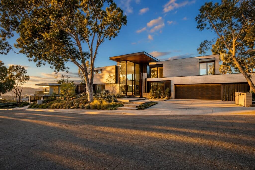 Modern luxury home with extensive glass walls and contemporary design on a hillside street in Porter Ranch's gated community.